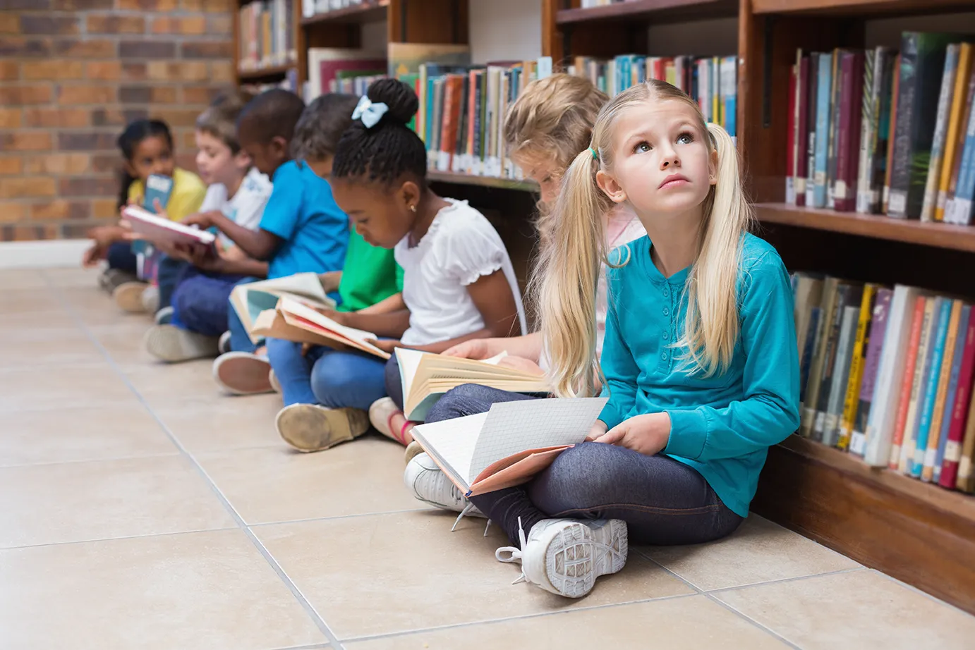 Она сидит в библиотеке. Дети сидят в библиотеке. Ученики сидят на полу. Sitting pupil. Дети в библиотеке сидящие по кругу фото.